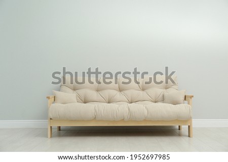 Stylish beige sofa near light wall indoors
