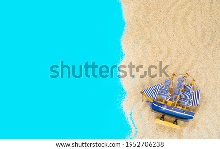Sand frame with a miniature ship on a blue background. Flat lay. Top view. Copy space. Vacation and travel concept