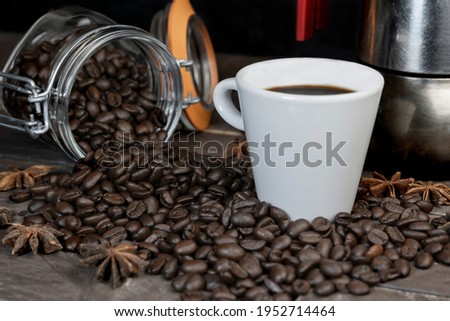 Roasted coffee beans with a white cup and moka pot.Espresso italian coffee maker on dark rustic wooden background with copy space.