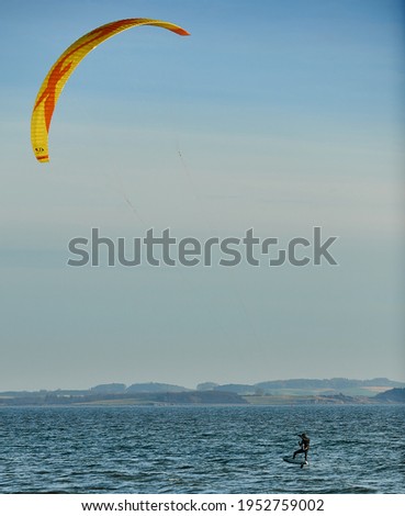 Denmark, Aarhus. Kite surfer play in the wind. The sea is reflected in the sun and the blue sky