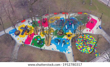 Children's colourful outside playground with carousels, swings and slides, among tall trees. in the forest park area, top view. Children playing at colorful park due to Covid-19 pandemic lockdown. 4k 