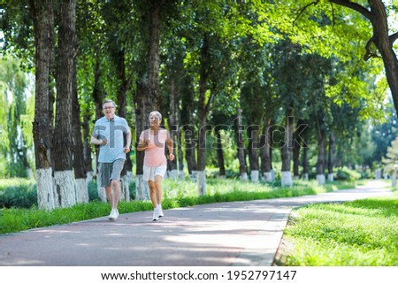 Old couple jogging in outdoor park smiling