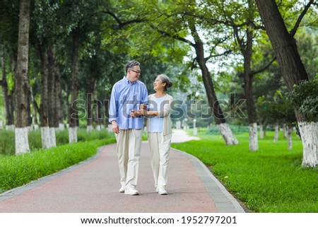Happy old couple walking in the park arm in arm