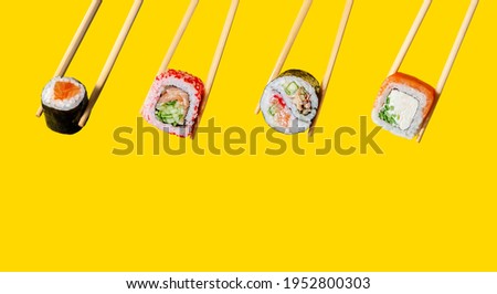 Close up Diversity Rolls. Maki, California, Yin-Yang and Philadelphia on chopsticks on yellow background
