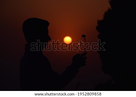 Beautiful picture of a boy and bottle in hand. Sunset in background