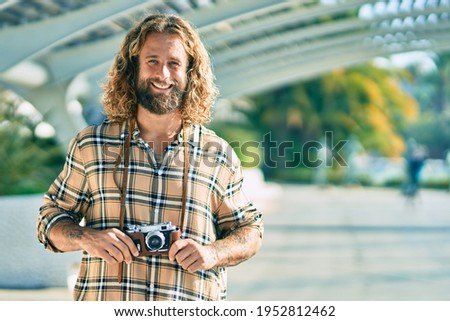 Young caucasian tourist man smiling happy using vintage camera at the park.