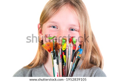 Happy child girl artist with brushes and palette in hands on white background. Painting education concept, art school