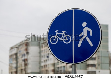 A road sign on the sidewalk indicating bicycle and footpaths. Background with place for text