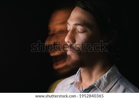 Portrait of a relaxed and calm Latin man with his eyes closed next to a distorted image of himself screaming and annoyed. Long exposure image. Double personality. Mental illness concept