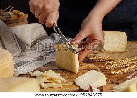Somebody hands cut a piece of  fresh homemade cheese on a wooden board close up Royalty-Free Stock Photo #1952843575