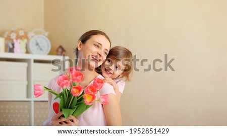 happy mother's day. baby daughter gives flowers to her mother for a holiday and gently hug her Mother