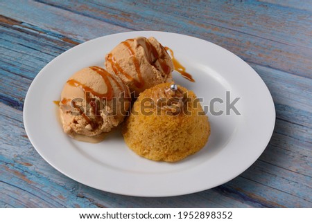 Cupcake with dulce de leche ice cream on a white plate on an old blue wooden table