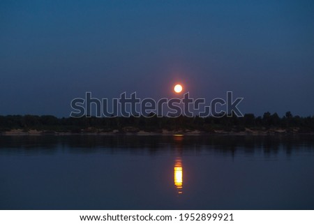 Natural landscape with night sky and moon reflected in water in the river. Soothing picture of tranquil nature. Perfect night scene