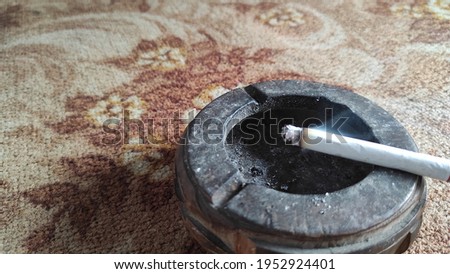 A cigarette burning in a wooden ashtray