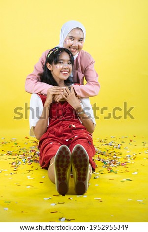 Closeup portrait of two young beautiful  asian woman isolated on yellow background.