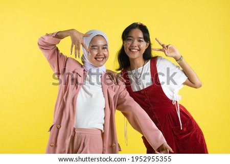 Closeup portrait of two young beautiful  asian woman isolated on yellow background.