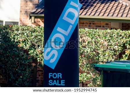 For sale sign near the residential building house with 'SOLD' sold sticker on it. Auction clearance rate