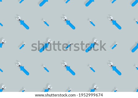Background from a metal adjustable wrench with a rubber handle. Tools seamless pattern.