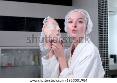Alginate mask. Funny photo with an air kiss. A mask in the hands of a patient in a beauty salon. The concept of keeping the skin young and toned. Health and facial care.