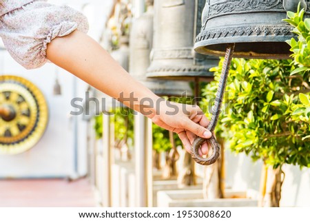Woman hand rings the old bell for Make a wish in the Wat Saket Golden Mountain Temple famous , Golden Mount is a Buddhist temple in Pom Prap Sattru Phai district, Bangkok. Royalty-Free Stock Photo #1953008620