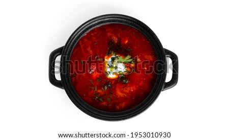 Red, hot borscht - beet soup with sour cream and herbs in black pot isolated on a white background. High quality photo