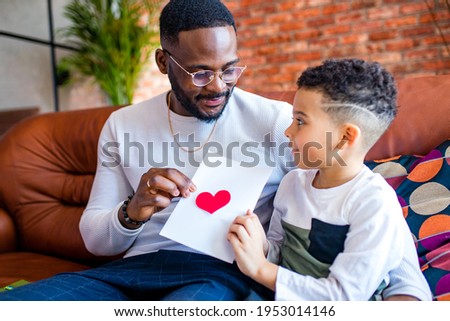 afro american baby giving to dad a Valentine's Day picture in living room