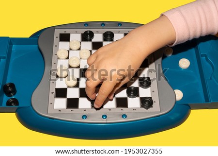The child's hand lies on the checkers board. The concept of pastime, leisure and games.