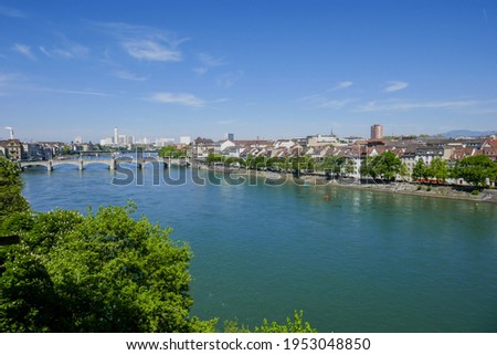 Sunny wide view over green spring trees, the river Rhine and the Mittlere Brücke (Middle Bridge) from the Münsterplatz or Pfalz terrace in Basel, Switzerland. Royalty-Free Stock Photo #1953048850