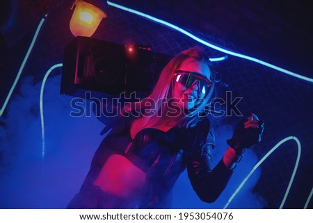 A young girl with a stereo cassette player is listening music and dancing in the neon lights on the dance floor.
