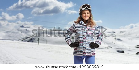 Young female with ski goggles posing on a snowy mountain 