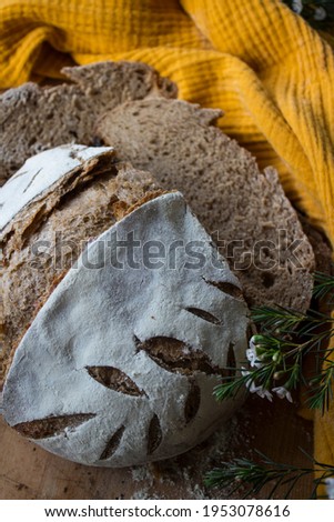 Round whole wheat bread on a table. Yellow fabric background. Top view photo of fresh baked sourdough bread. 