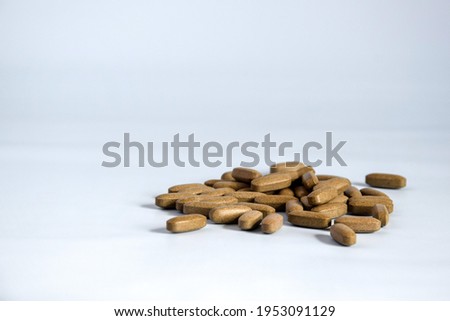 Natural brown pressed medicinal herb, pills on blue background. Alternative medicine concept of drugs, tablets, medicines and pills. Copy space. Selective focus. Royalty-Free Stock Photo #1953091129