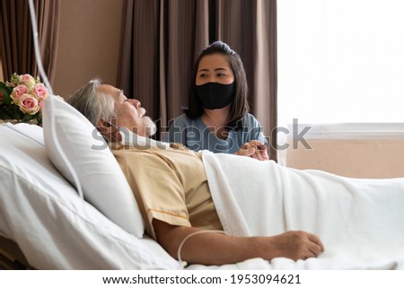 Senior elderly man lying on patient bed and woman visiting sitting beside him, holding his hand and hopes for recovery in patient room in the hospital Royalty-Free Stock Photo #1953094621