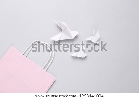 Origami pigeons and shopping package on gray background