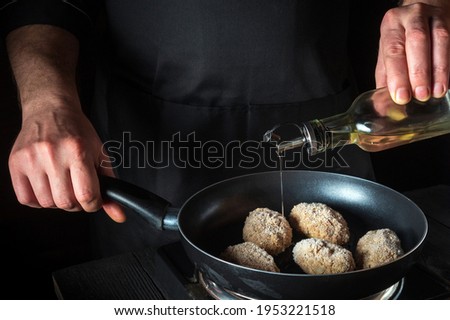 Cooking beef cutlets in a grill pan with the hands of a chef on a black background for copying the space text restaurant menu. Chef adds oil
