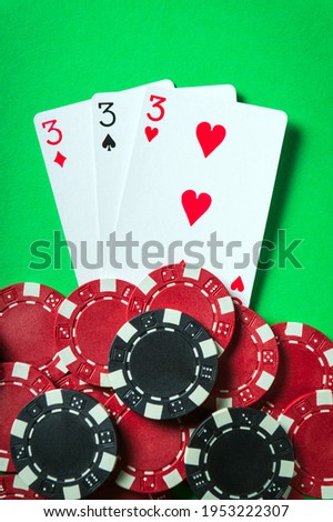 The winning poker combination is three kind or set. Chips and cards on green table in the poker club