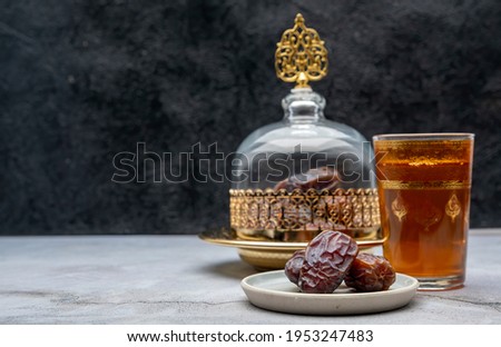 Date in Glass dome and gold plate on table side view with writing space.Ramadan and Welcome concept.Black background.