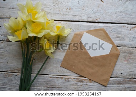 Artistic mockup for your artwork with beautiful flowers, kraft paper envelope and empty card shot from the top. Flat lay minimalistic composition with space for text.