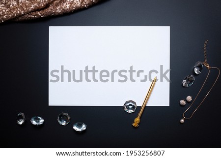Elegant background, template for text or logo. White, empty paper sheet, jewellery and other accessories on the black background. Free space, copy space. Fashion, beauty backdrop.