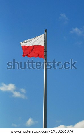 The state flag of Poland on a pole on a background of blue sky in the wind day
