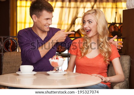 beautiful blond sitting with ice-cream on nose. handsome guy putting cream on girl face