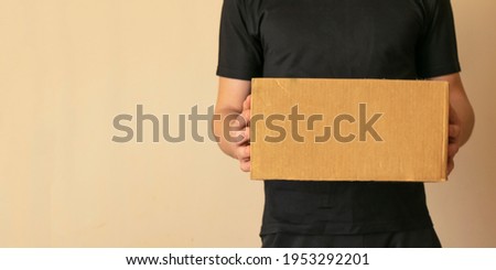 banner delivery man in black clothes hold a cardboard box.