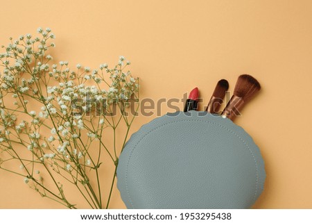 Cosmetic bag and gypsophila flower on beige background