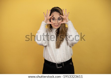 Pretty woman with long hair Trying to open eyes with fingers, sleepy and tired for morning fatigue against yellow wall