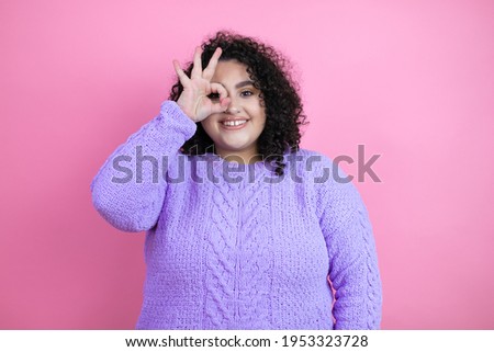 Young beautiful woman wearing casual sweater over isolated pink background doing ok gesture shocked with smiling face, eye looking through fingers