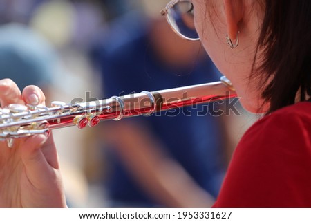 a girl in a red t-shirt plays the flute at a city party on a sunny day