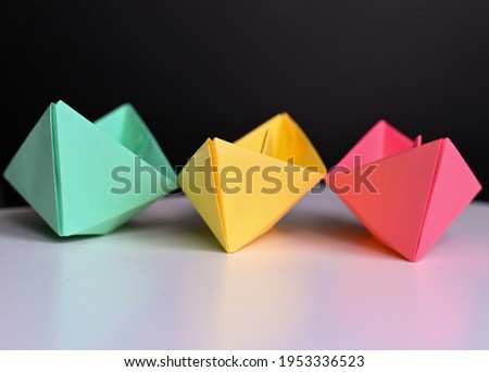 multicolored paper boats on a white background