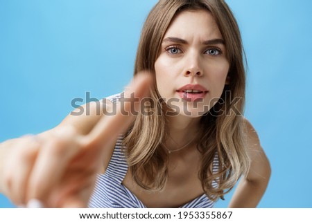 Curious and intrigued woman poking at camera with finger as if checking anyone there looking at her, bending forward with serious interested expression frowning, pressing forefinger to lense Royalty-Free Stock Photo #1953355867