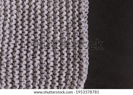 Wool handmade gray knitted pattern over black background. Horizontal image.