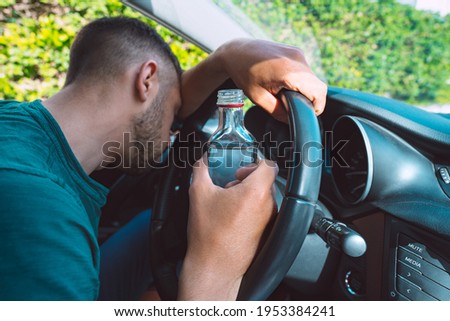 Drunk man sleeping on the steering wheel in his car with a bottle of vodka in his hands. Drunk driver Royalty-Free Stock Photo #1953384241